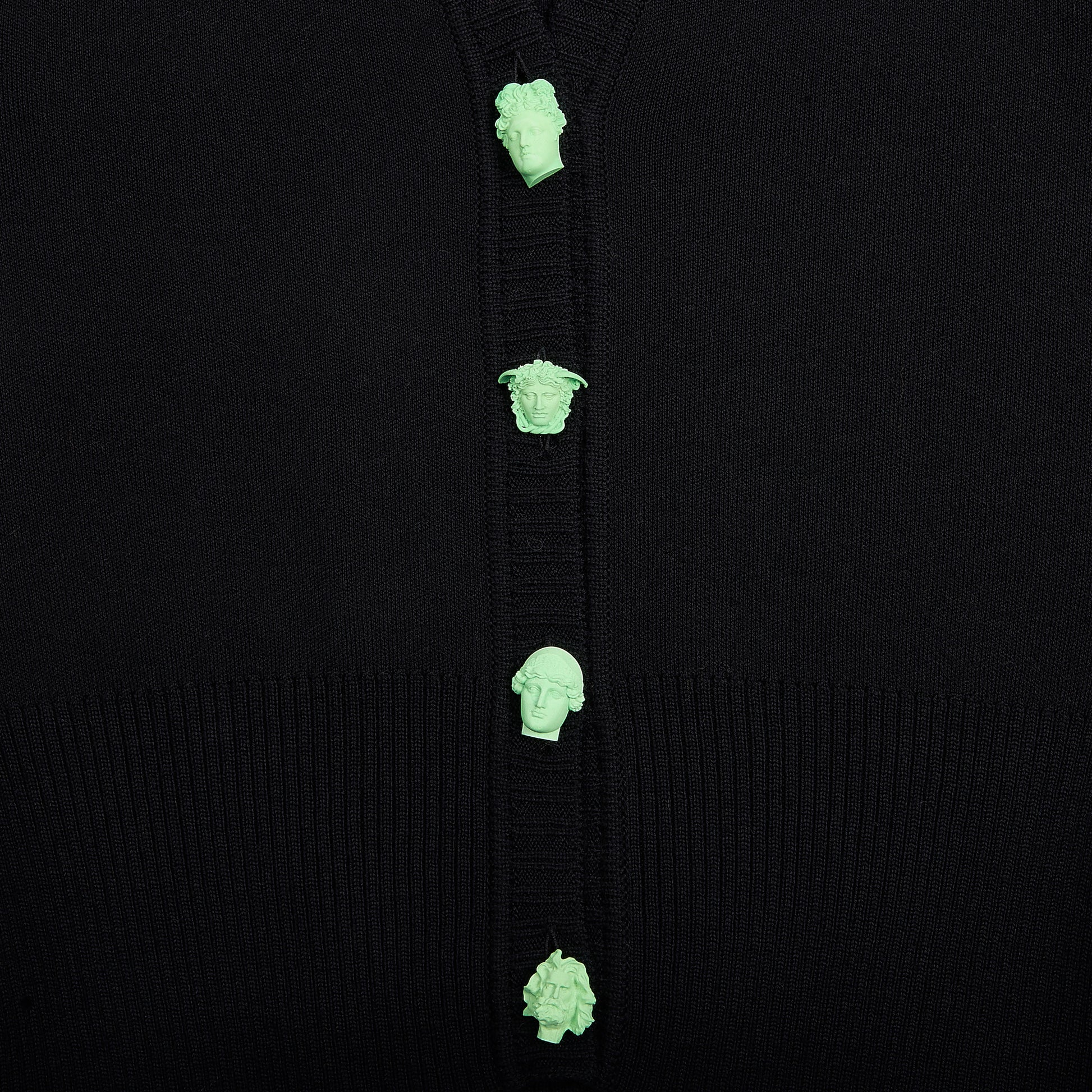 Close-up of a black ribbed knit cardigan featuring four mint green Greek Mythology buttons down the front.