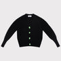 A black knit cardigan sweater with long sleeves featuring four light green decorative Greek Mythology buttons down the front, laid flat against a light gray background.