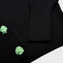 Close-up of a black ribbed knitc ardigan featuring two bright mint green sculptural Greek Mythology buttons.