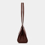 A dark brown leather shoulder bag shown from the back, featuring a single long strap and a structured triangular silhouette, set against a plain light gray background.