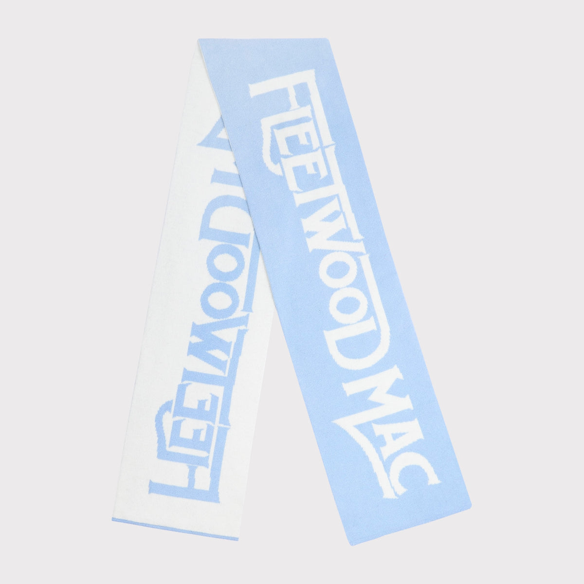 A light blue knit scarf with 'Fleetwood Mac' knitted across. The scarf is shown folded against a solid light grey background.
