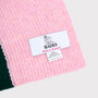 An image of the HADES made in Scotland label upclose on the Forest Green and Pink hooded scarf. 