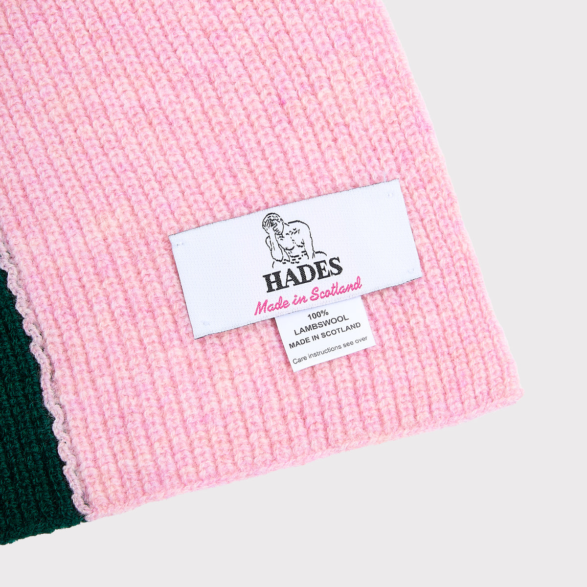 An image of the HADES made in Scotland label upclose on the Forest Green and Pink hooded scarf. 