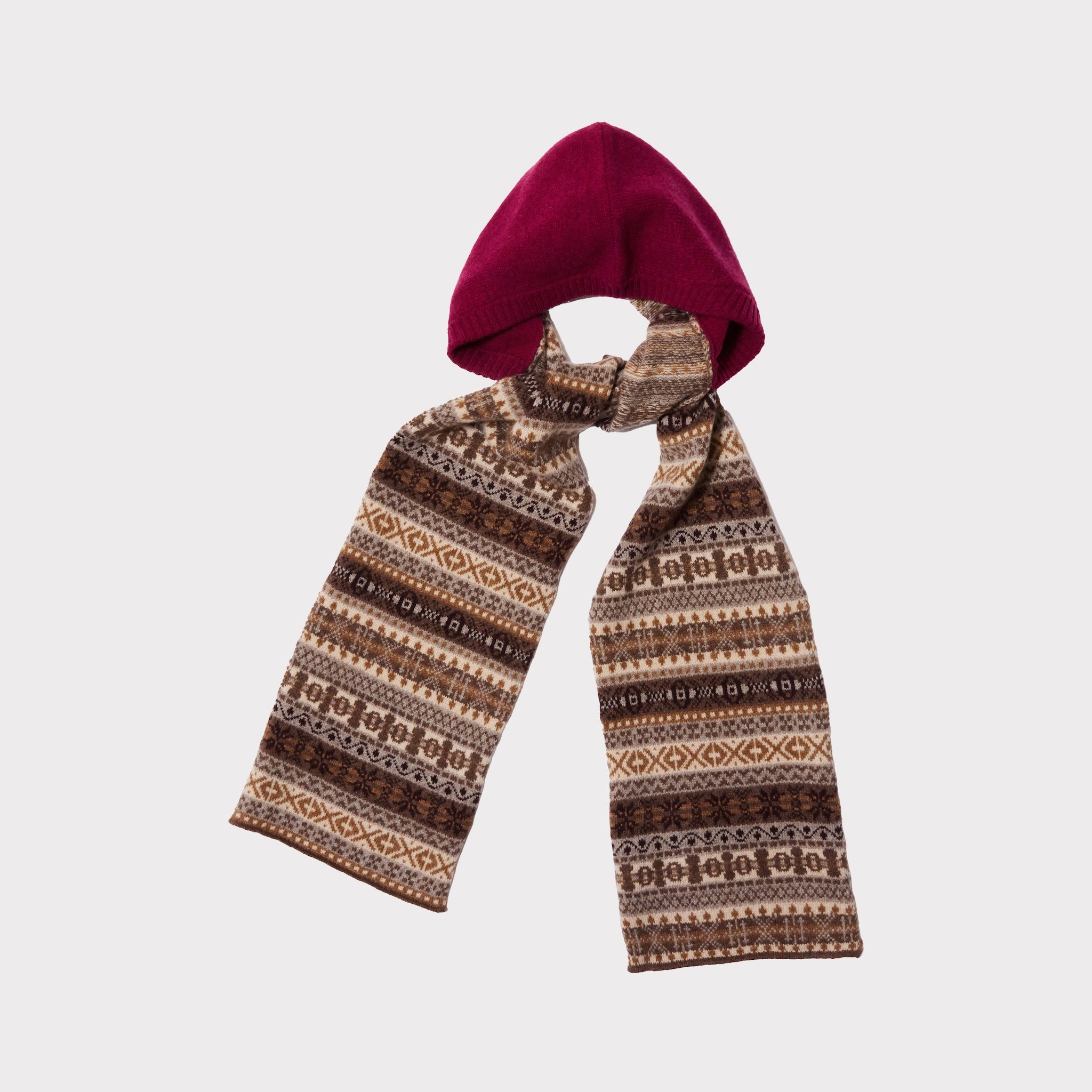 An image of The Berry & Brown Fair Isle hooded scarf tied in a knot on a light grey background. 
