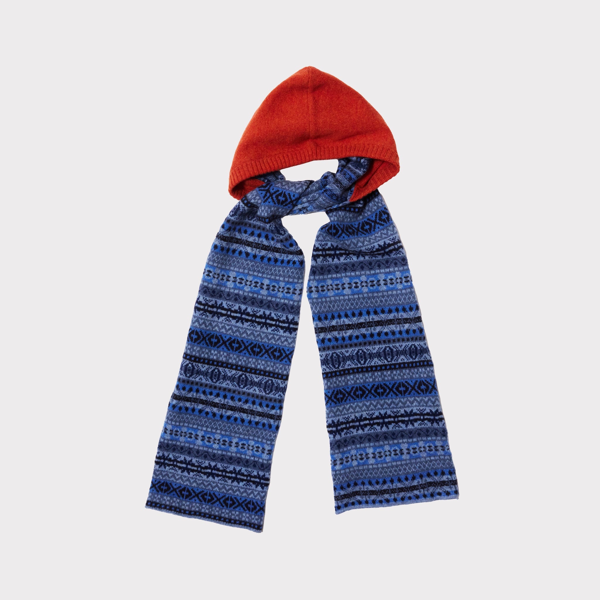 An image of The Burnt Orange & Blue Fair Isle hooded scarf tied in a knot on a light grey background. 