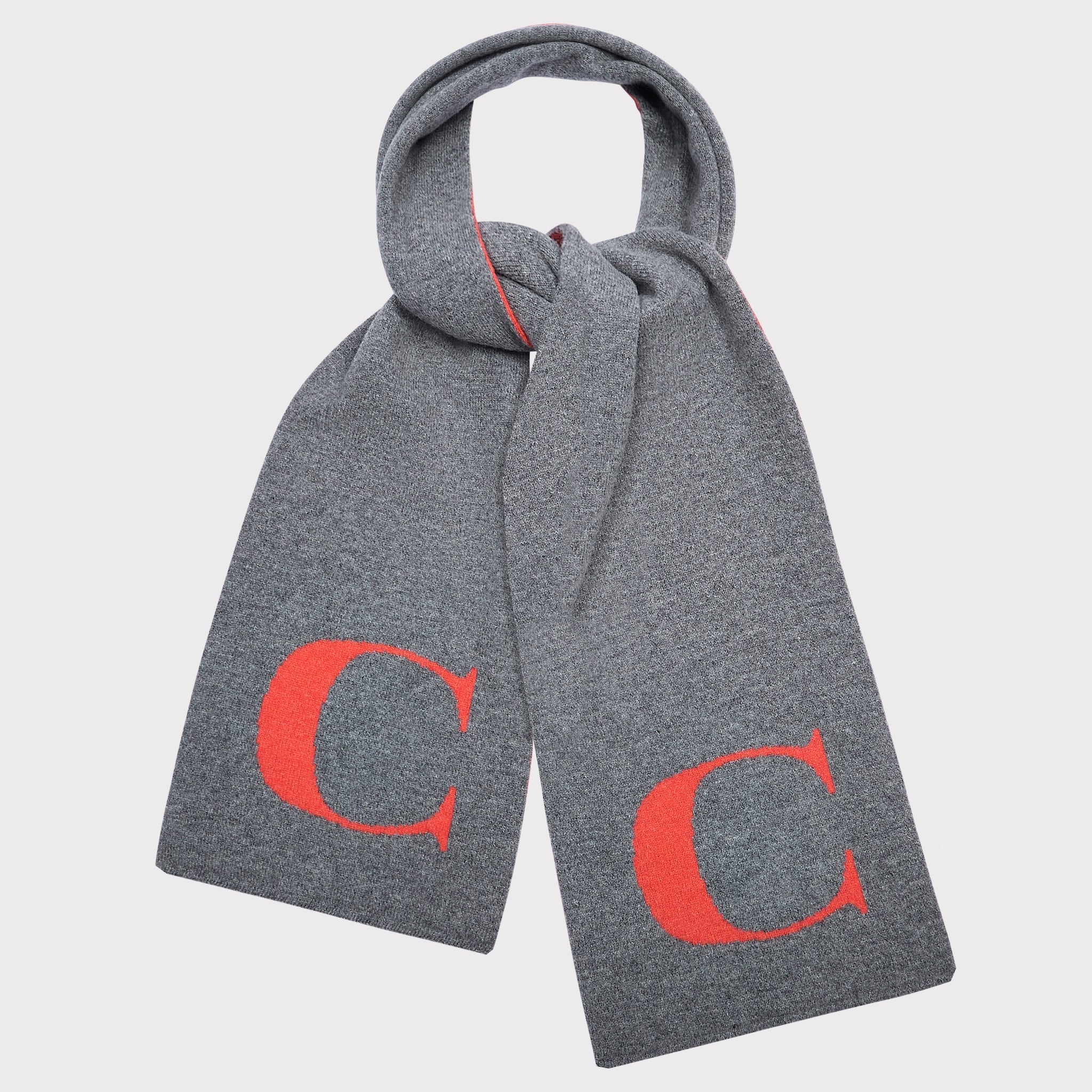A grey knit scarf with a large orange serif letter 'C' printed on each end, shown tied in a loop against a light grey background.