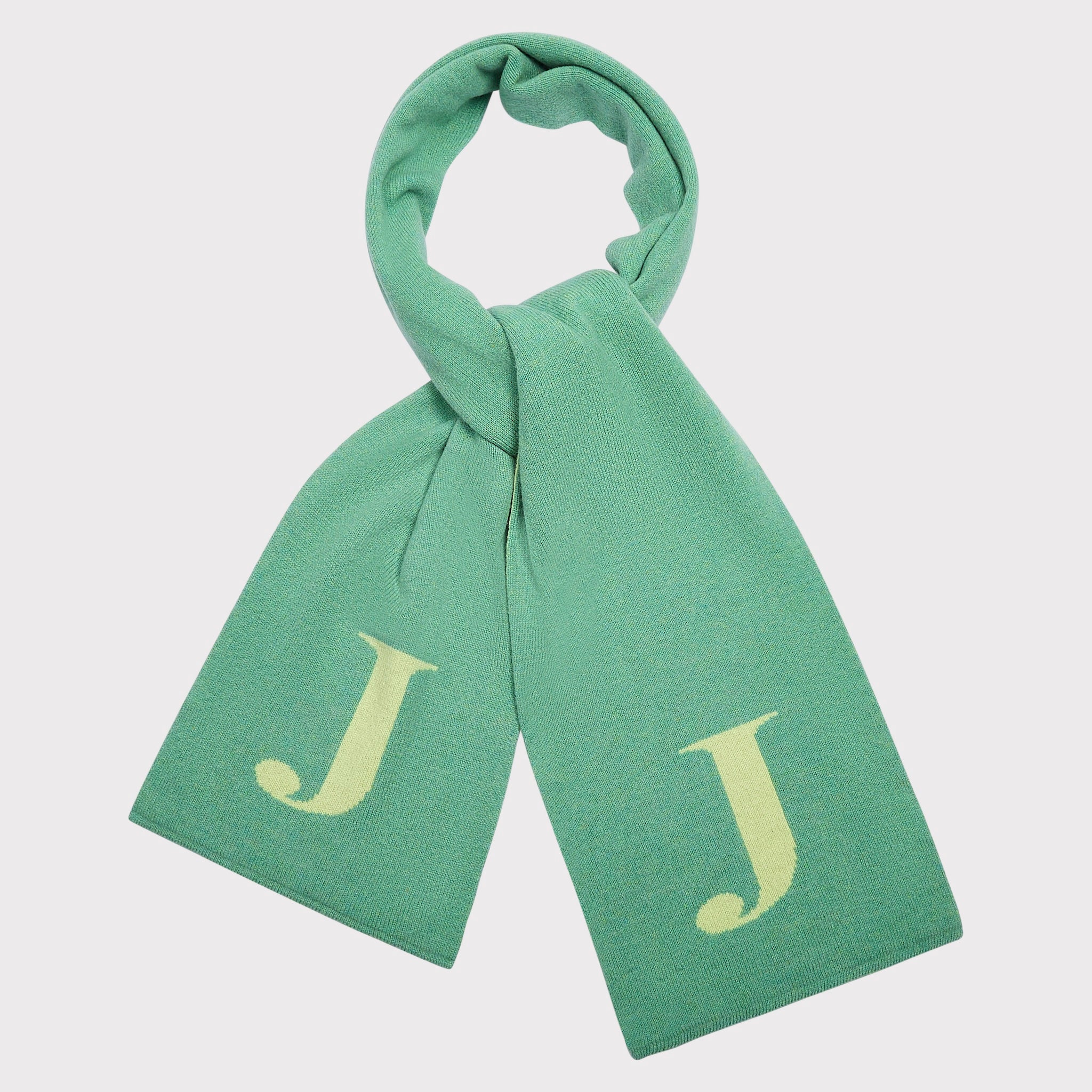 A mint green knit scarf with the letter 'J' on each end, shown tied in a loop against a light grey background.