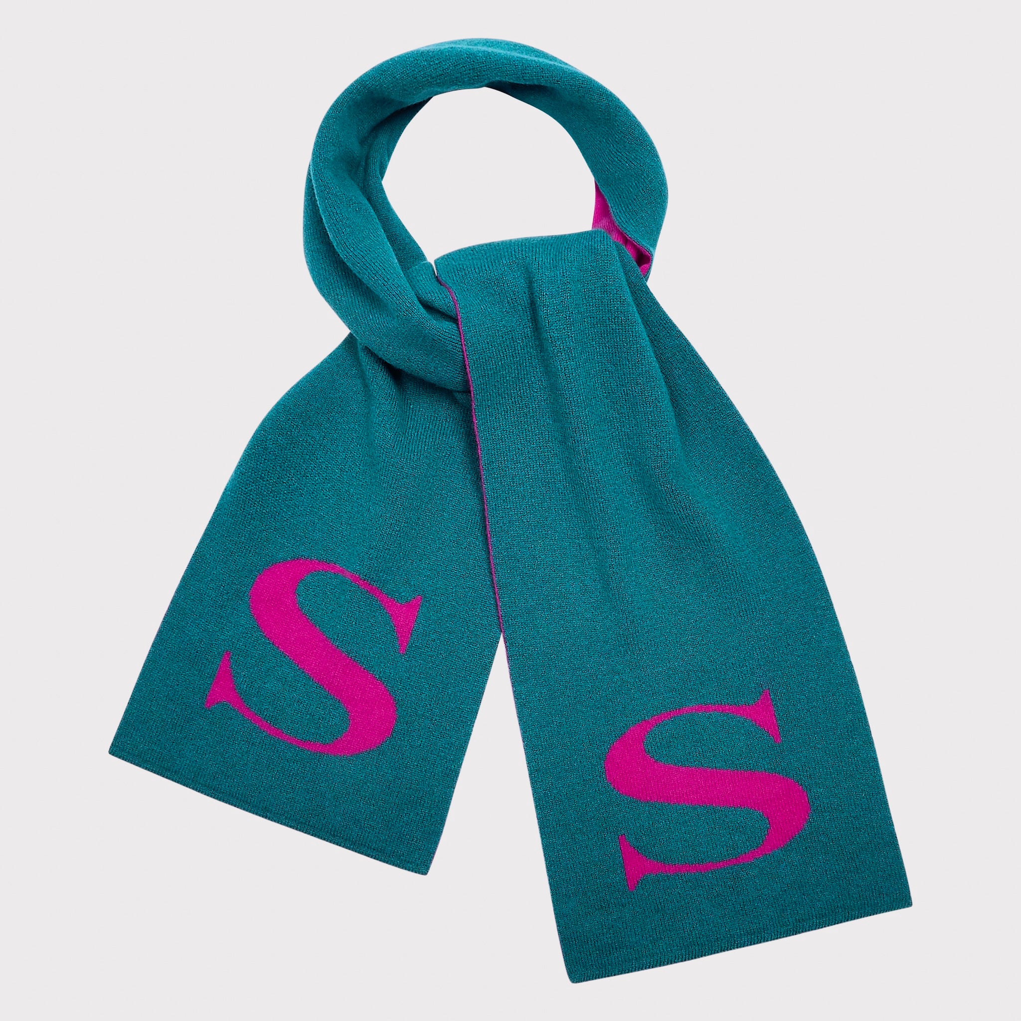 A ocean green knit scarf with a deep pink monogram letter 'S' on each end, shown on a light grey background.