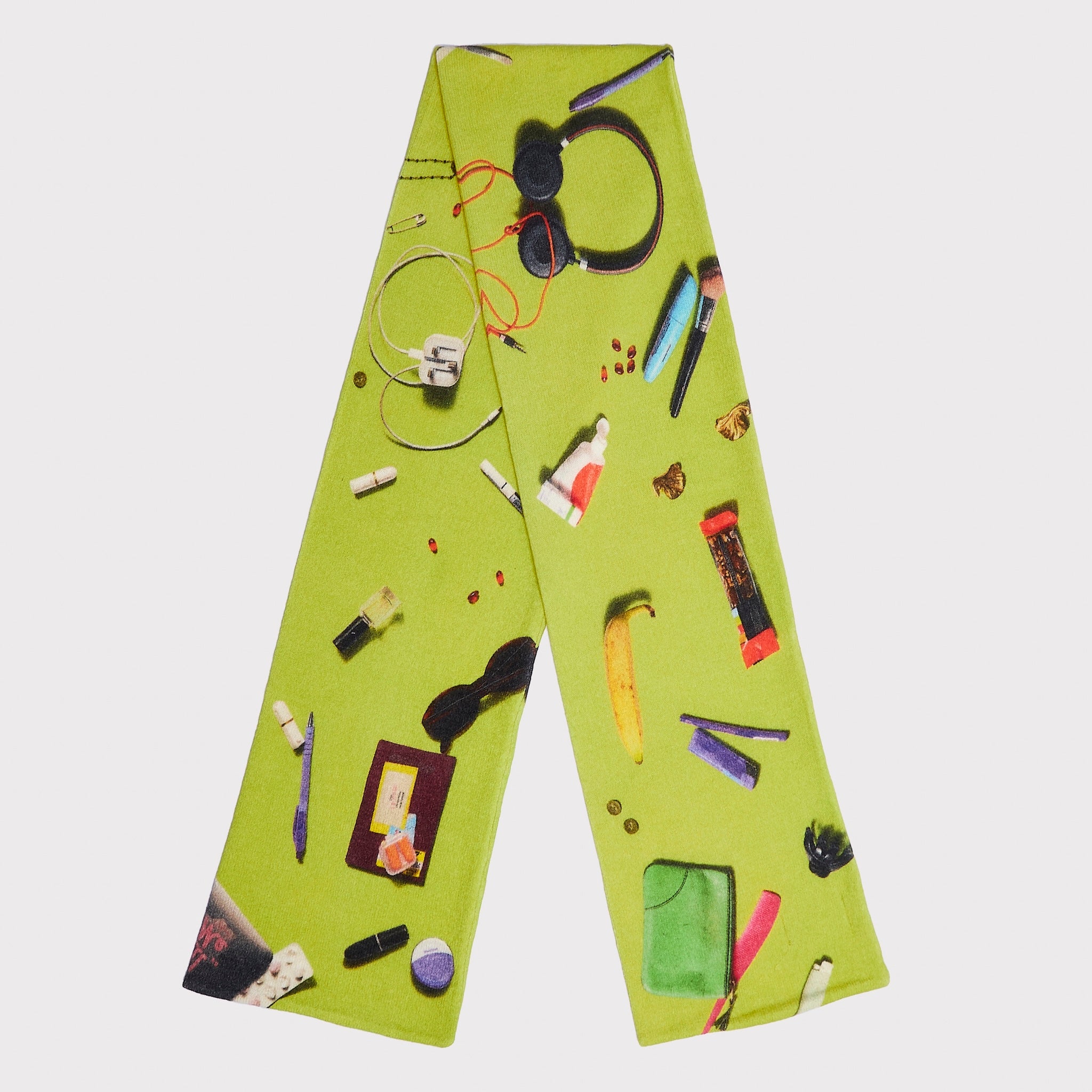 An image the HADES Handbag lime green knit scarf featuring the contents of a handbag such as pink lipstick, a banana, a hair clip, a purple compact, and a black pen.