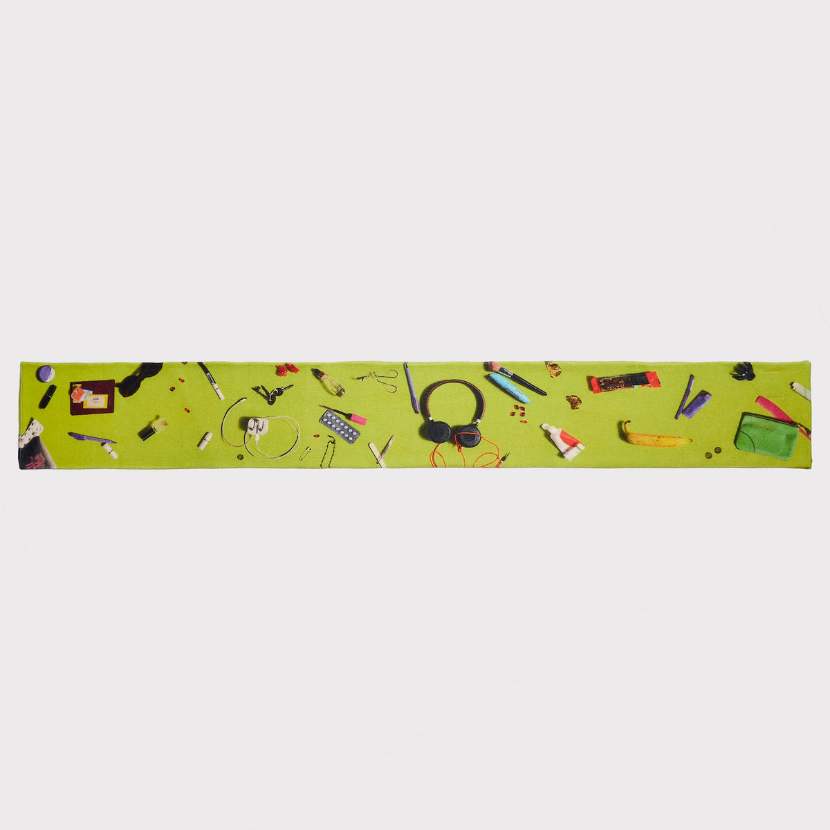 An image of the HADES Handbag scarf in bright lime green, printed with a variety of Handbag contents including headphones, a camera, a camera strap, a pencil shown flat against a light gray background.
