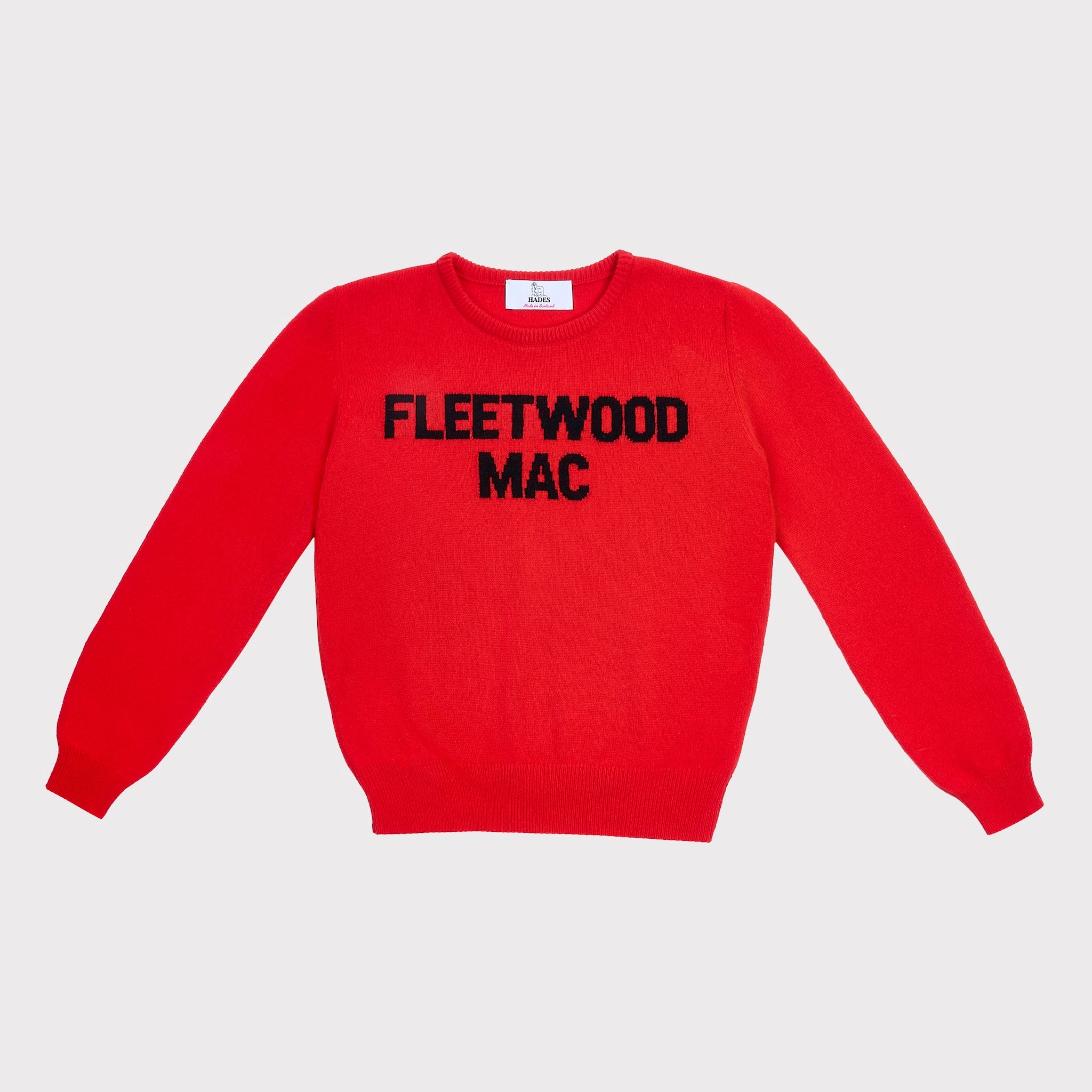 A bright red crewneck sweater with 'FLEETWOOD MAC' knitted in black across the chest, displayed flat against a light grey background.