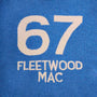 Close-up of a blue knit fabric with large cream-colored numbers '67' and the text 'FLEETWOOD MAC' knitted below.