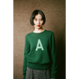 Person wearing a green sweater with a letter 'A' on a brown background