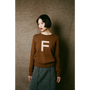 Person wearing a brown sweater with a white 'F' on a plain background