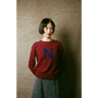 HADES model wearing burgundy jumper with a blue letter 'N' 