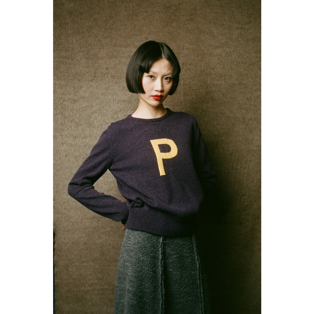 Model wearing HADES dark purple jumper with a yellow letter 'P' 