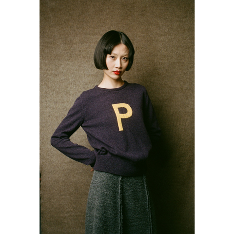 Model wearing HADES dark purple jumper with a yellow letter 'P' 