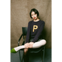 Woman sitting on a chair wearing HADES dark purple sweater with a yellow letter 'P' 