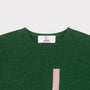 HADES green jumper with a pink letter 'J' necklabel