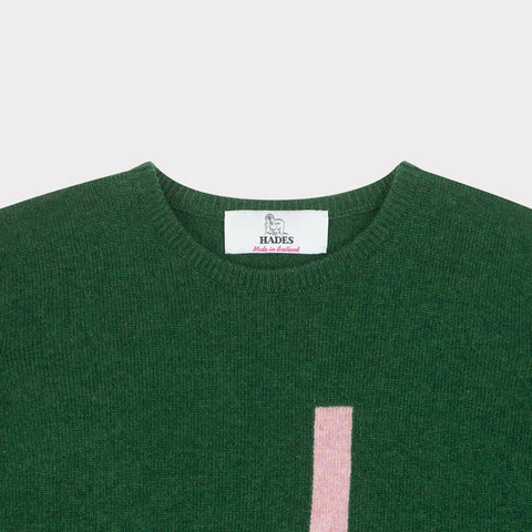 HADES green jumper with a pink letter 'J' necklabel