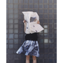 An image of a model wearing the Egos Arcady Skirt, holding a newspaper in front of her face. 