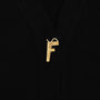 Up close shot of the F gold plated button featured on the FU*K Carrington cardigan