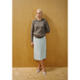 A lady wearing the Armour Knit and Delusion skirt against a wooden backdrop