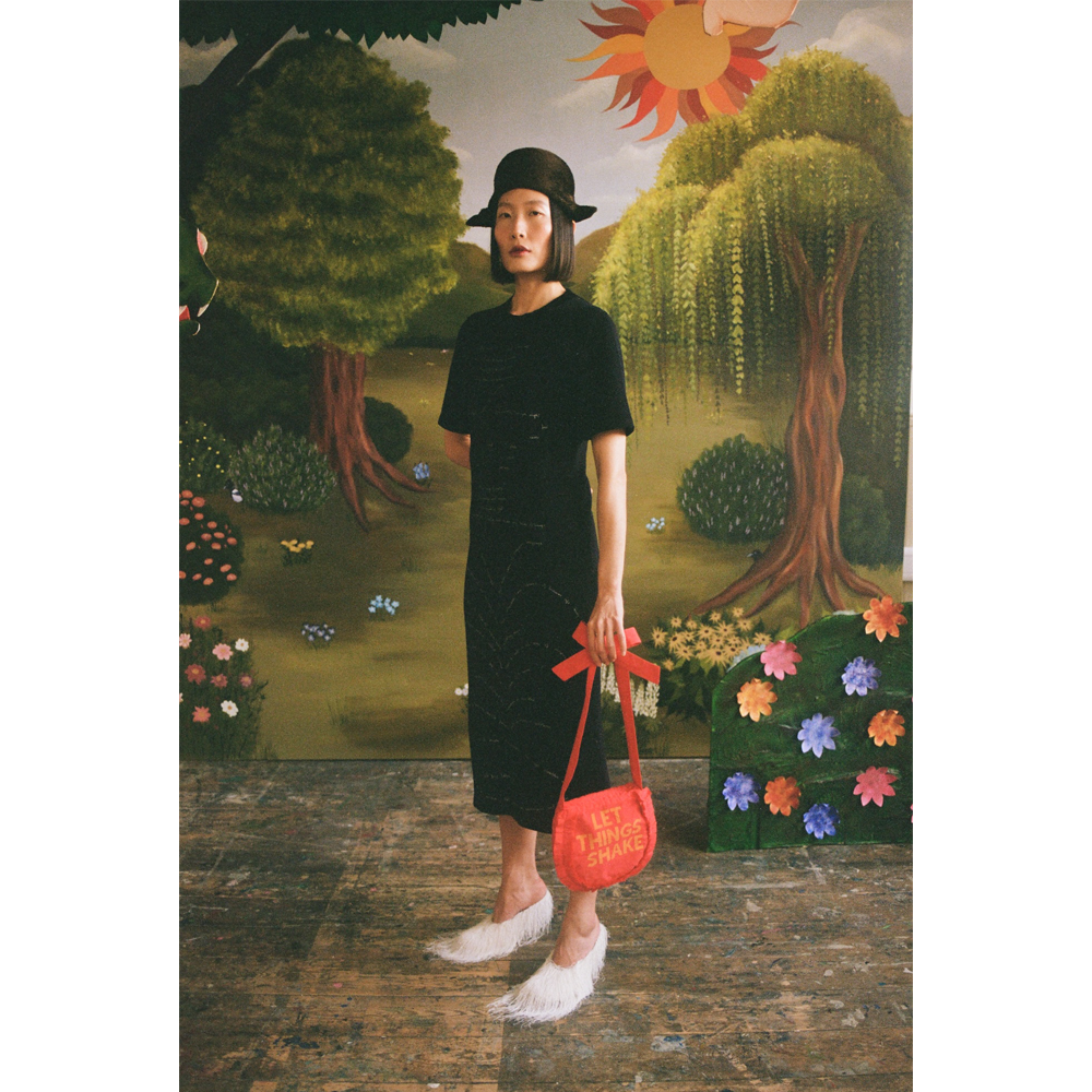Model wearing the Dear Fellow Humans" dress in front of a faux garden of eden backdrop.