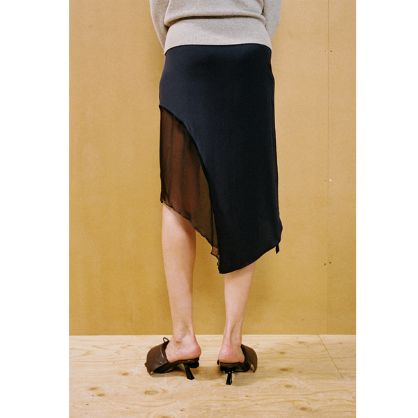Close up of a lady wearing the Delusion skirt against a wooden backdrop