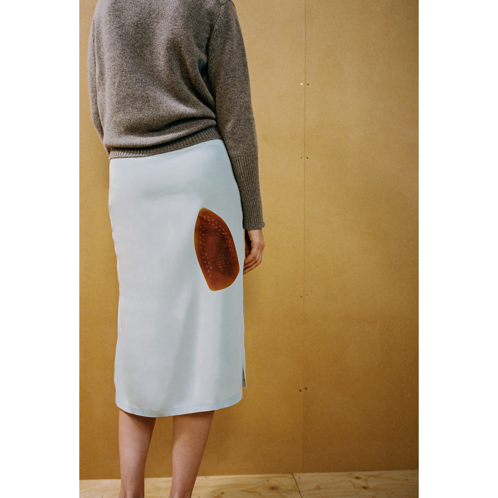 Close up of a lady wearing the Iron Burn skirt against a wooden backdrop 