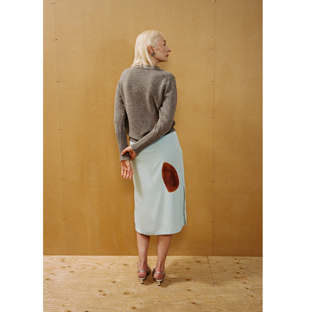 Lady wearing the Armour Knit and Iron Burn Skirt in front of a wooden backdrop