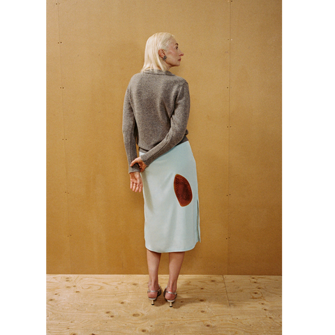 Lady wearing the Armour Knit and Iron Burn Skirt in front of a wooden backdrop