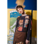 Person wearing The Opposite cardigan by HADES wool with artistic designs in front of a colorful abstract painting.