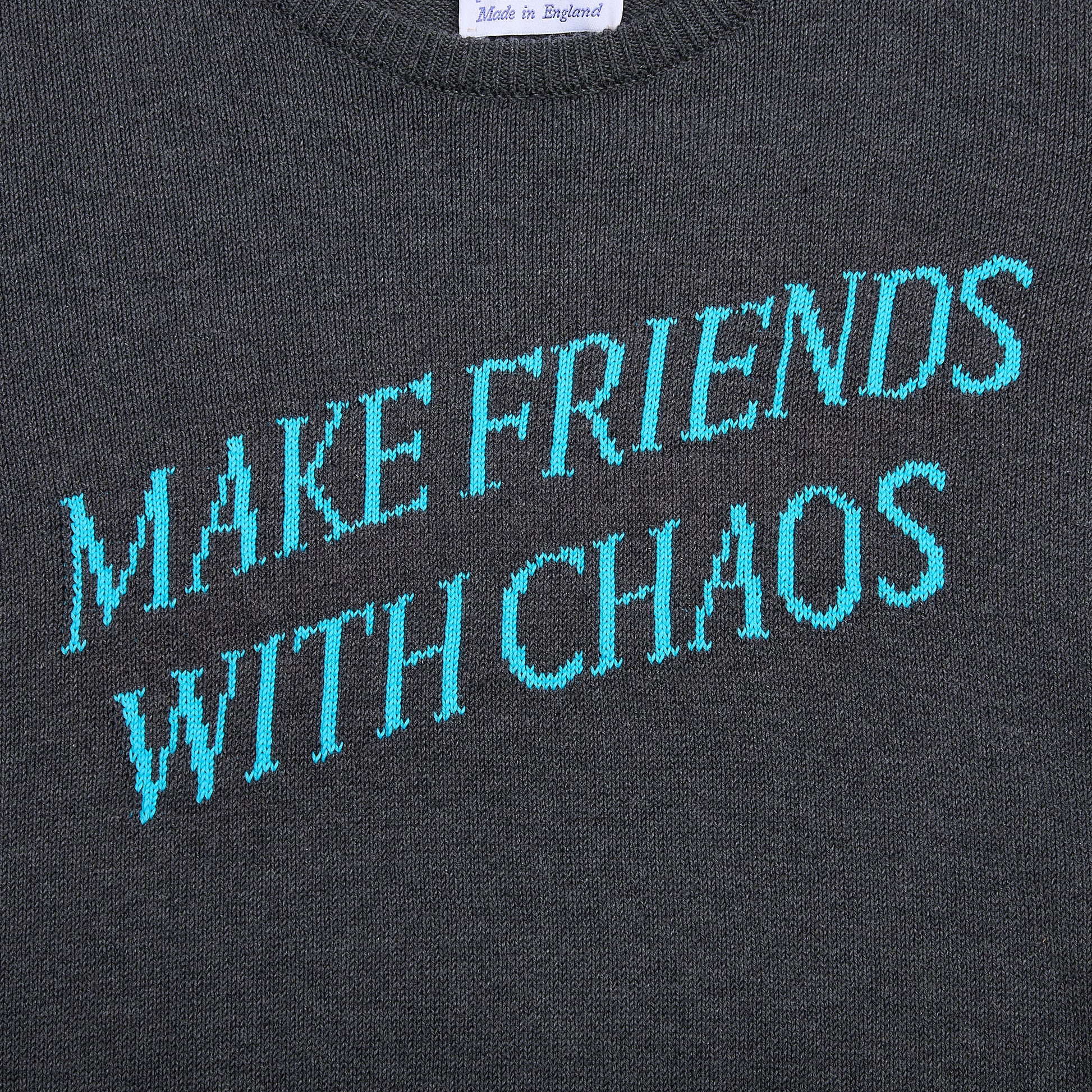 Close up flatshot of the "Make Friends With Chaos" knit in grey.