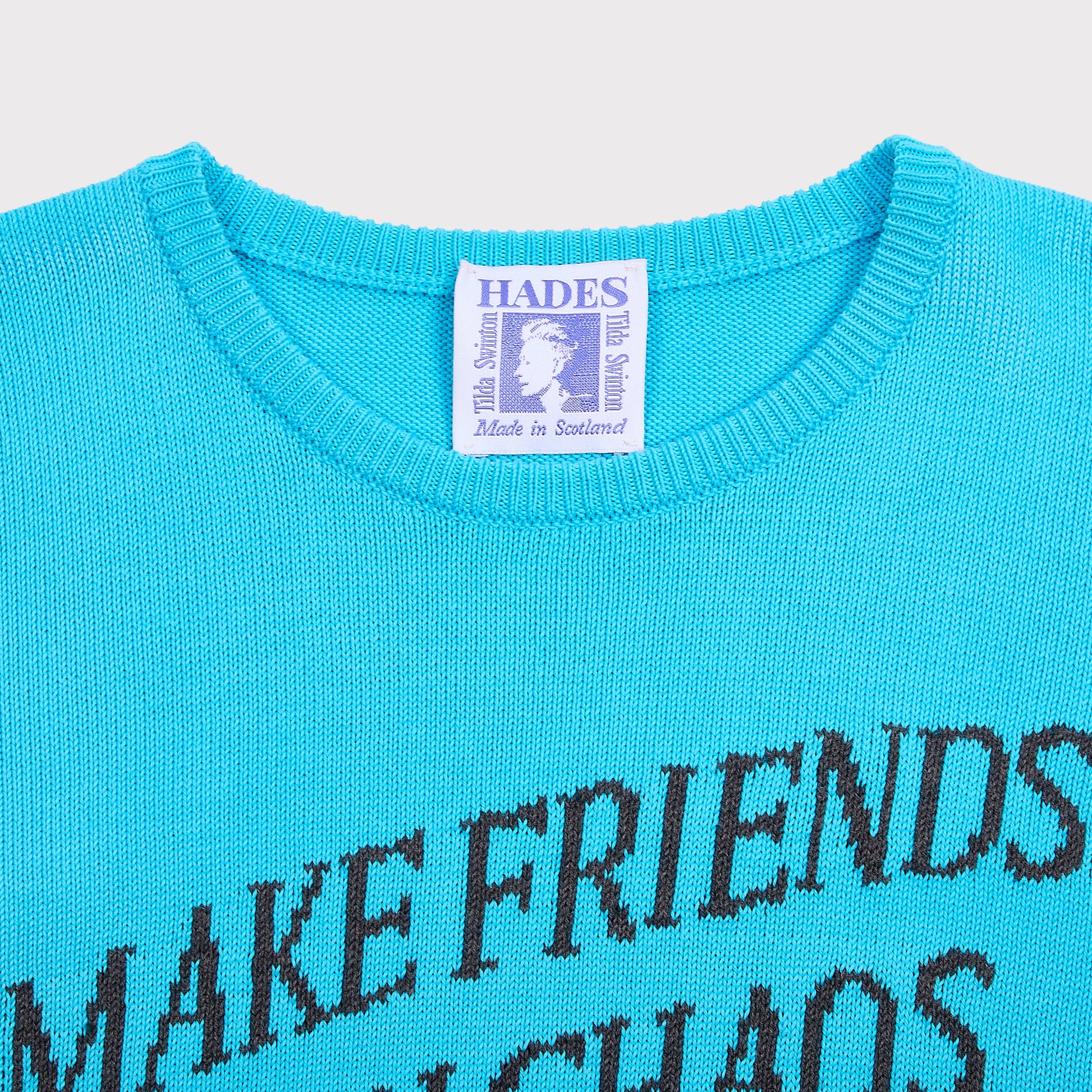 Close up shot of the "Make Friends With Chaos" knit and Tilda Swinton label. 