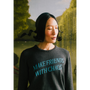 Model wearing a "Make Friends With Chaos" knit against a faux garden of eden.