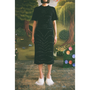 Model wearing the Dear Fellow Humans" dress in front of a faux garden of eden backdrop.